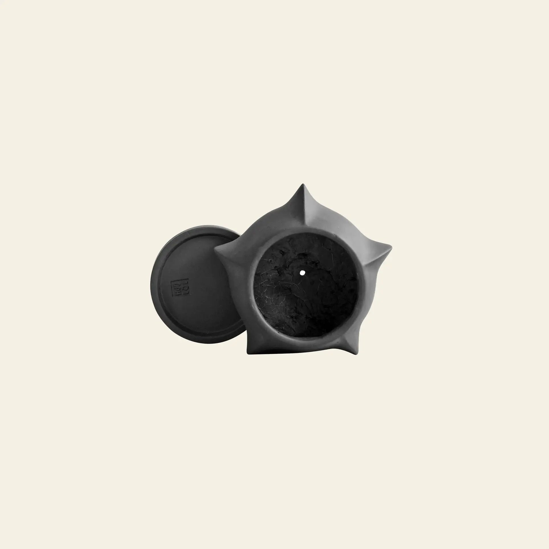 The 101 Copenhagen Arket Plant Pot, Petit by 101 Copenhagen is a matte black, star-shaped sculptural pot with architectural lines and a matching round lid, displayed from above on a plain, light background.