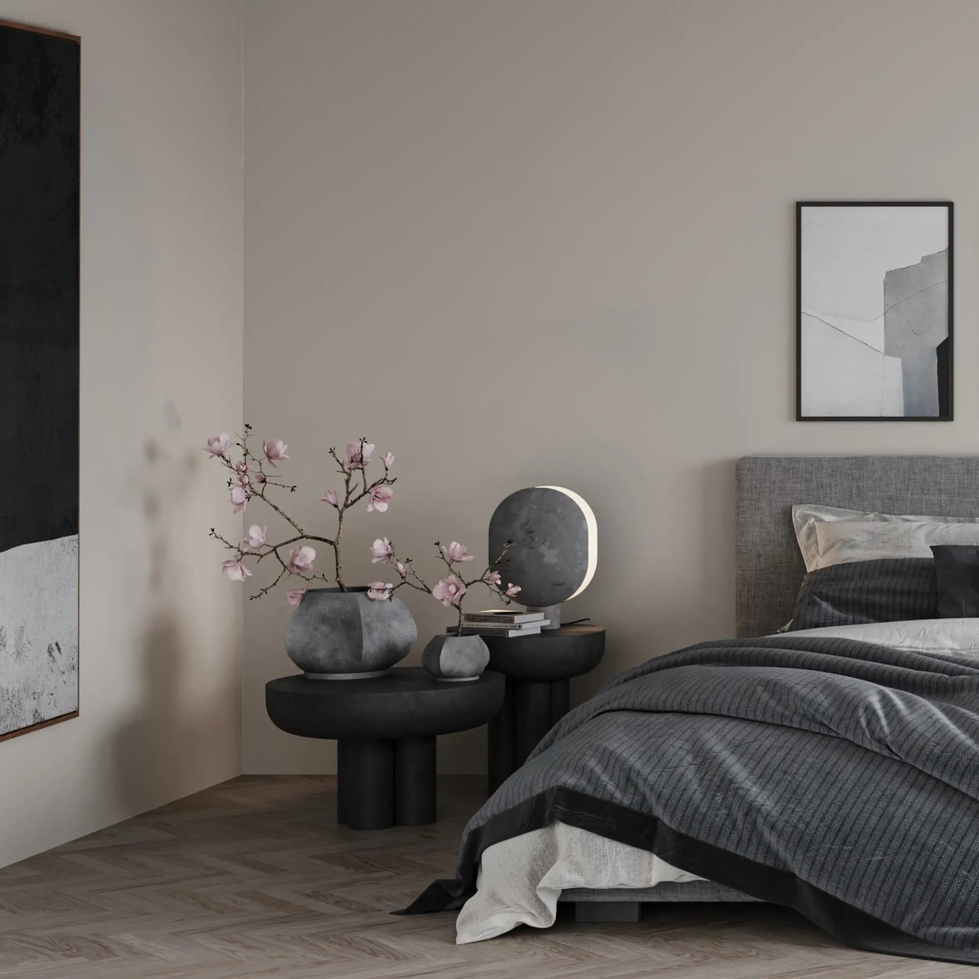 A modern bedroom in neutral tones features a gray bed, dark bedside tables, vases of pink flowers, a round lamp, minimalist black-and-white wall art, and the 101 Copenhagen Arket Plant Pot (Petit) for a touch of sculptural elegance.