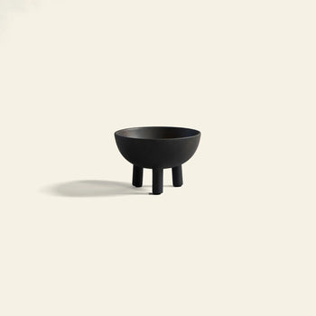 The 101 Copenhagen Duck Bowl, Big by 101 Copenhagen features a minimalist black ceramic design with three short legs, standing on a light beige background and casting a soft shadow—an ideal piece for Scandinavian-inspired interiors.