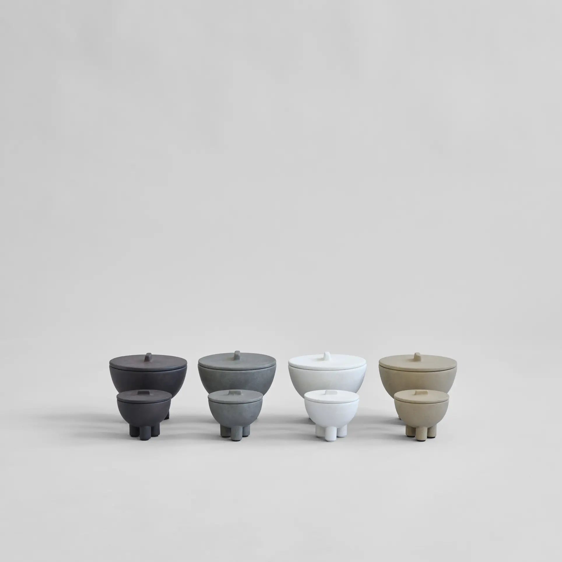 Five minimalist 101 Copenhagen Duck Jar, Medio containers are arranged in a row against a light gray background. Each jar features hand-glazed shades of black, gray, white, and beige—perfect decorative storage from 101 Copenhagen.