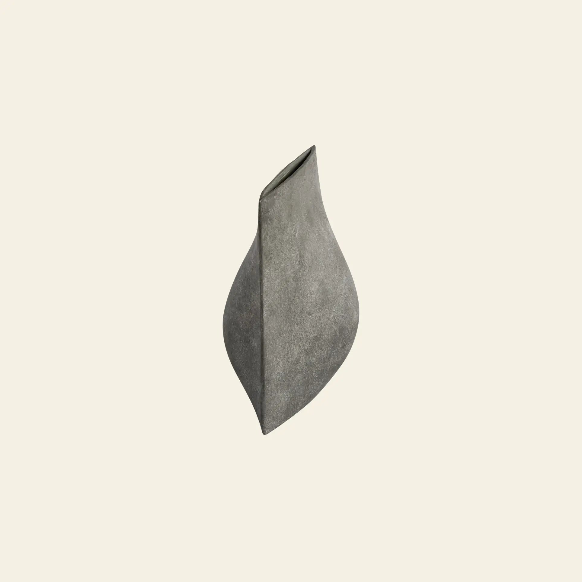 The 101 Copenhagen Origami Vase, Mini by 101 Copenhagen is a sculptural gray ceramic piece with a twisting, asymmetrical form inspired by Japanese art, showcased against a plain light beige background.