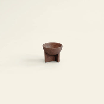 The 101 Copenhagen Osaka Bowl, Mini, by 101 Copenhagen, is a small, round brown ceramic bowl with a distinctive geometric base, showcased centered on a plain light beige background and inspired by sculptural Osaka bowls.