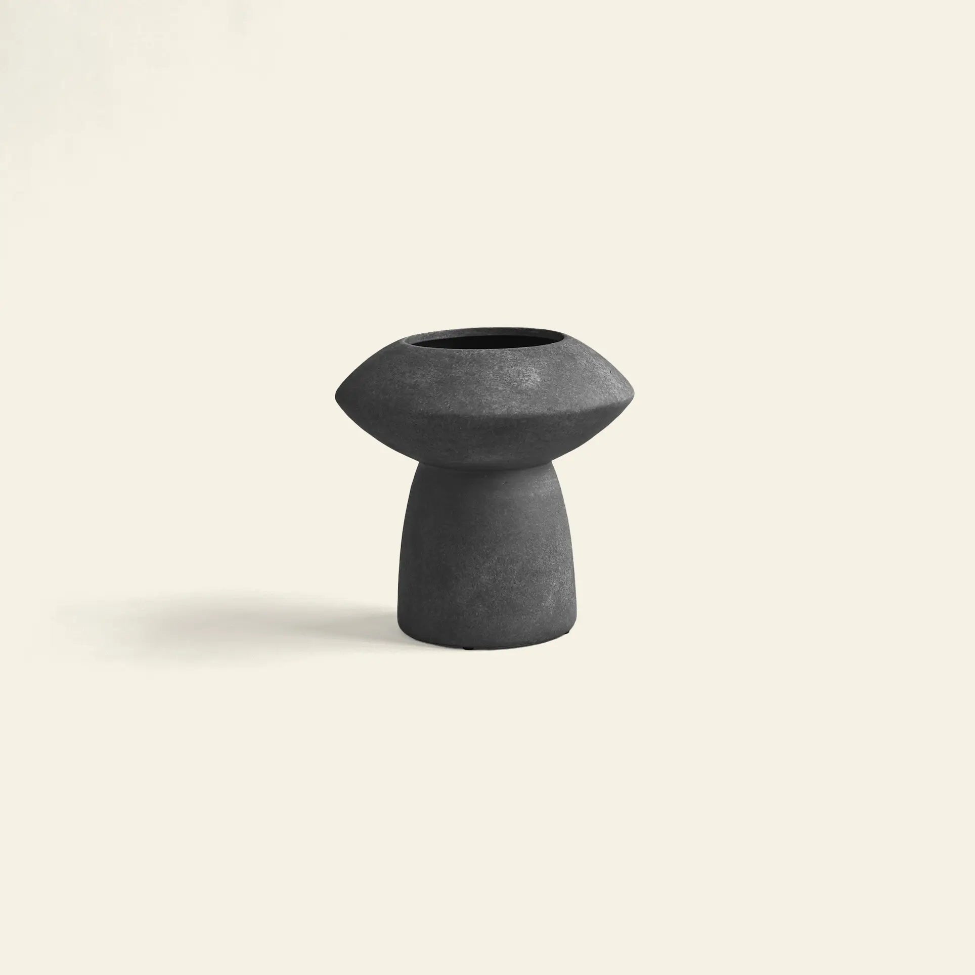 The 101 Copenhagen Sphere Vase Fat by 101 Copenhagen, in modern black with a wide top and narrow base, sits centered on a light beige background, exuding timeless elegance as an eye-catching centerpiece.