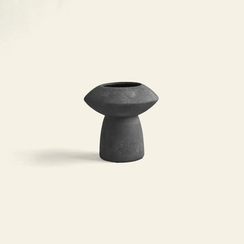 The 101 Copenhagen Sphere Vase Fat by 101 Copenhagen, in modern black with a wide top and narrow base, sits centered on a light beige background, exuding timeless elegance as an eye-catching centerpiece.