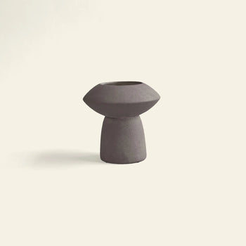 The 101 Copenhagen Sphere Vase Fat by 101 Copenhagen features a minimalist design with a wide, rounded top and narrow base in dark purple ceramic, bringing timeless elegance as a striking centerpiece against light backgrounds.