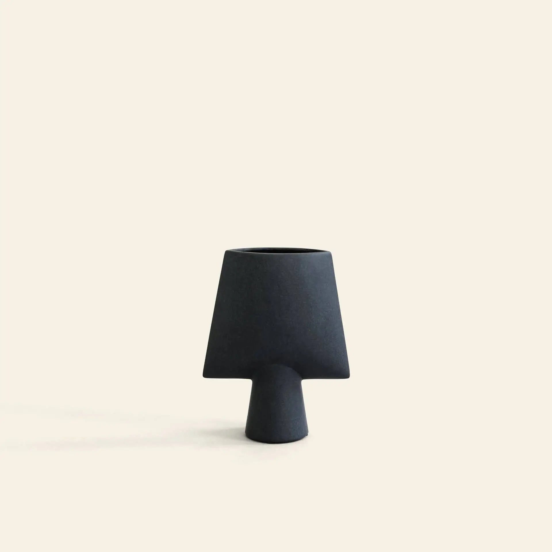 The 101 Copenhagen Sphere Vase Square, Mini by 101 Copenhagen features a small, matte black geometric design with a wide top and narrow base—ideal for modern décor—shown centered on an off-white background.
