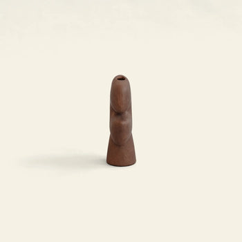 The 101 Copenhagen Tribal Vase, Mini by 101 Copenhagen is a small, abstract wooden sculpture with smooth curves and an opening at the top, standing upright against a plain, light background.