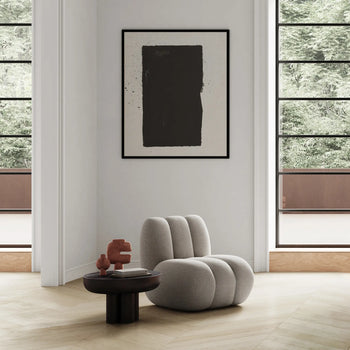 Minimalist interior with a plush light gray lounge chair, round wooden side table featuring the 101 Copenhagen Tribal Vase, Mini by 101 Copenhagen, large windows, and a black-and-white abstract painting on the wall.