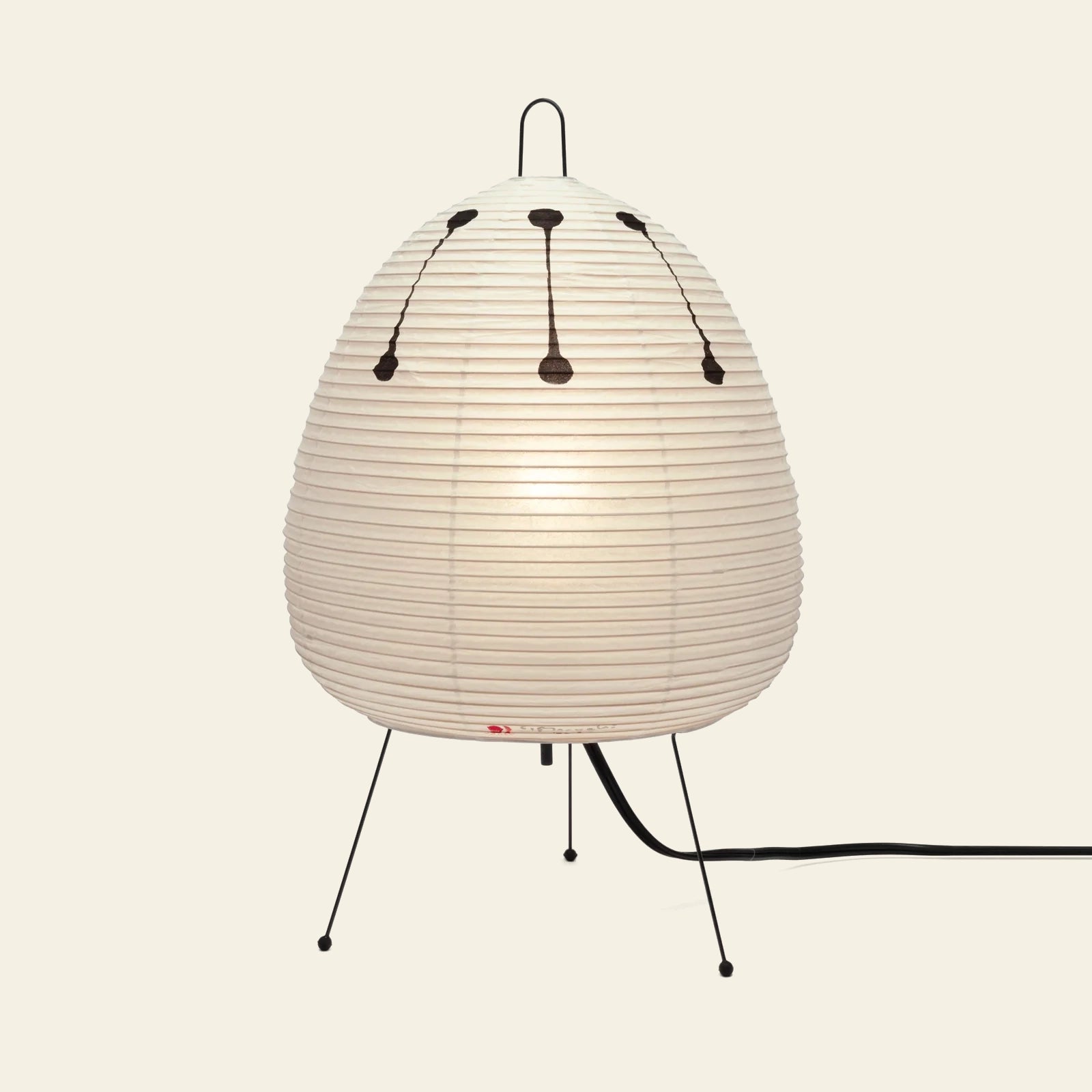 The Akari 1AD by Akari is a round, white, ribbed paper lantern lamp inspired by Japanese craftsmanship, featuring three black legs, a top black handle, and a visible power cord against a light background.