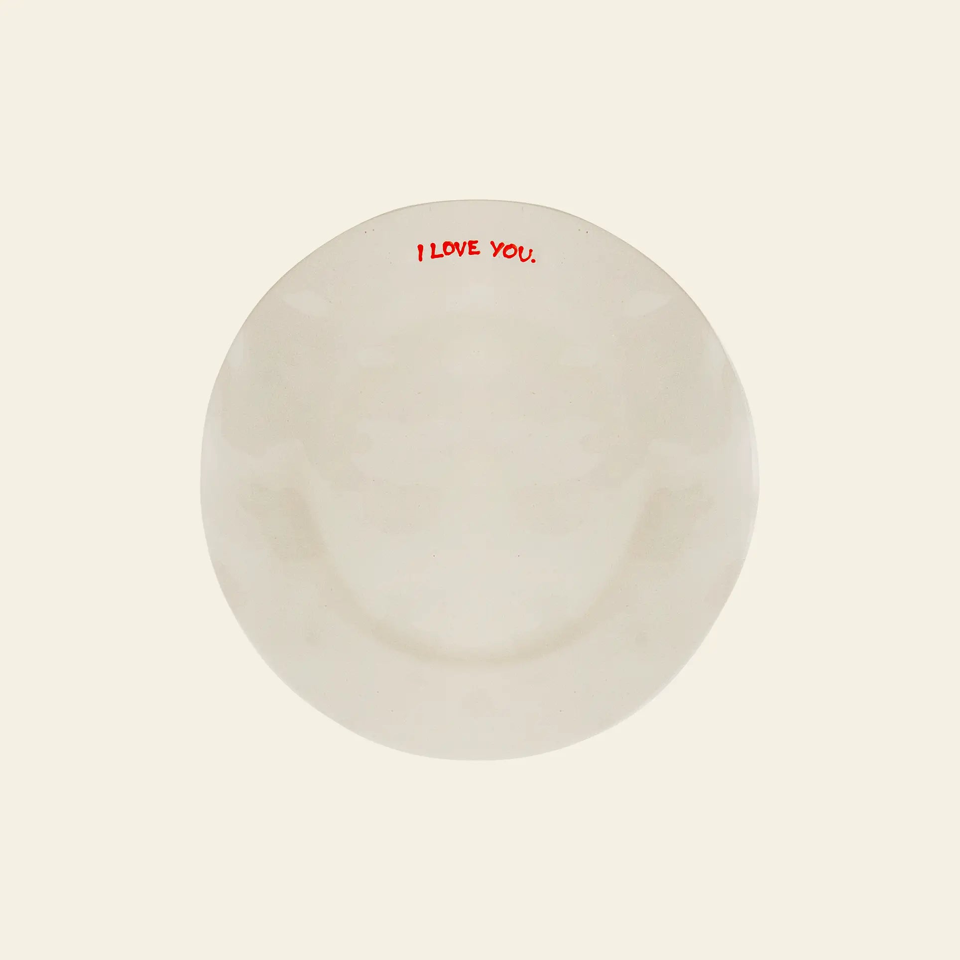 The Anna + Nina I Love You Breakfast Plate features I LOVE YOU. in bold red letters along the rim—ideal for breakfast in bed. The background is light beige, and its a charming ceramic piece from Anna + Nina.