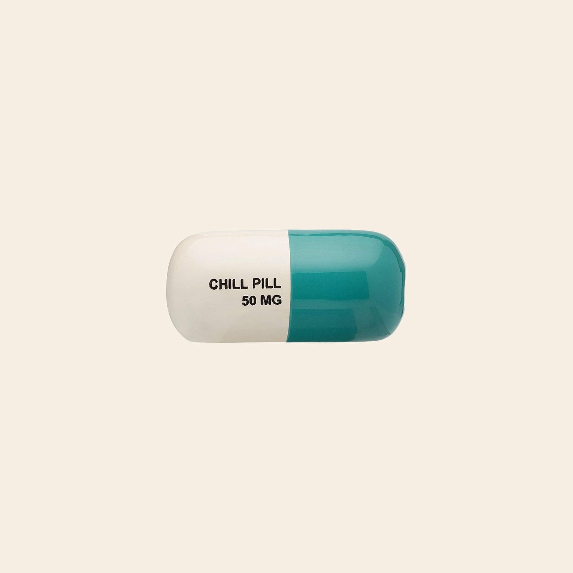 The Anna + Nina Chill Pill Figure, a blue and white capsule labeled CHILL PILL 50 MG, rests on a plain beige background, making a quirky decorative piece from the Anna + Nina brand.
