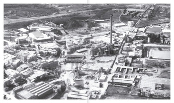 A black-and-white aerial view of an industrial complex—factories, warehouses, chimneys, and tracks—reflecting the adaptive reuse found in Apartamento La Fábrica by Ricardo Bofill, from Apartamento.