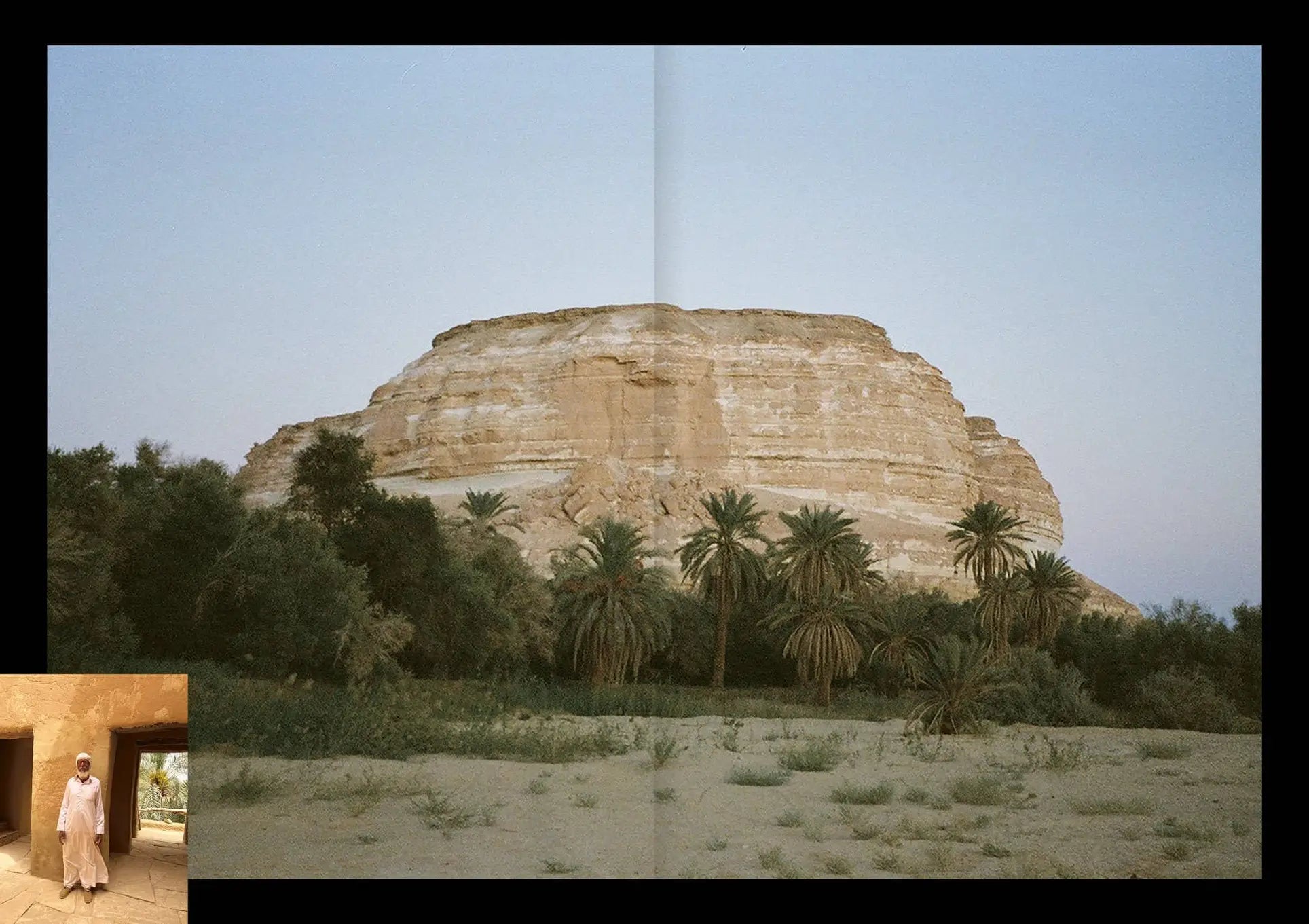 On the cover of Apartamento Magazine Issue #29 by Apartamento, a rocky hill towers over palm trees beneath a clear sky; in the lower left, an inset shows a person in traditional clothing standing in a stone doorway.