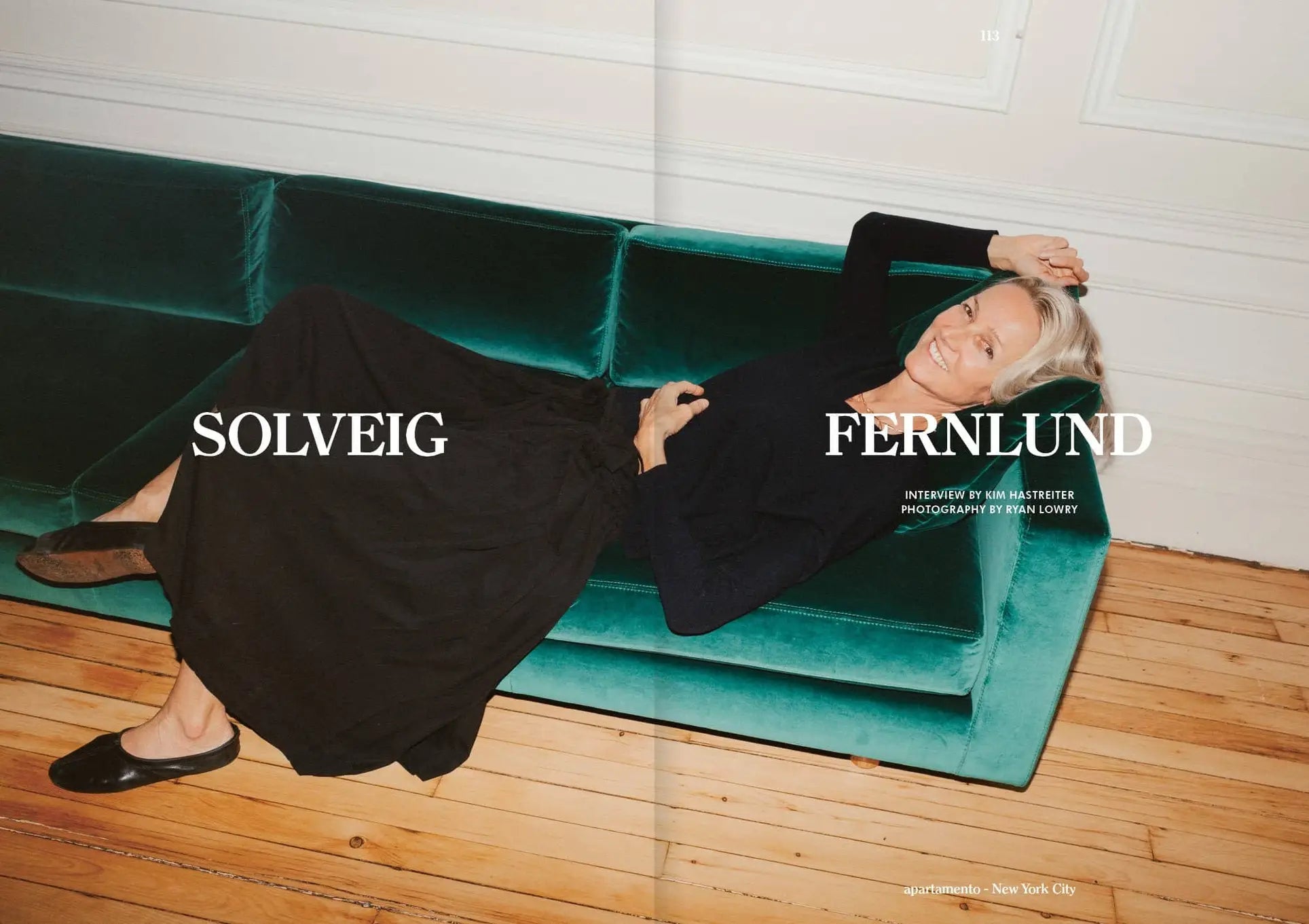 A smiling woman with short blonde hair reclines on a green velvet sofa, wearing a black long skirt and sweater. Text over the image reads Apartamento Magazine Issue #29 by Apartamento.