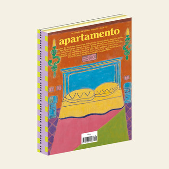 The cover of Apartamento Magazine Issue #31 by Apartamento shows an illustrated bed with yellow pillows, a green, pink, and yellow blanket, blue nightstands and lamps, set against an orange and red backdrop.