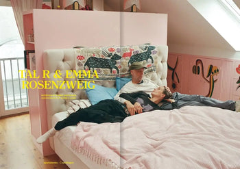 A couple lounges on a pink bed in a vibrant room—playful wall art and patterns capture the essence of Spring Summer 2023, as seen in Apartamento Magazine Issue #31 by Apartamento.