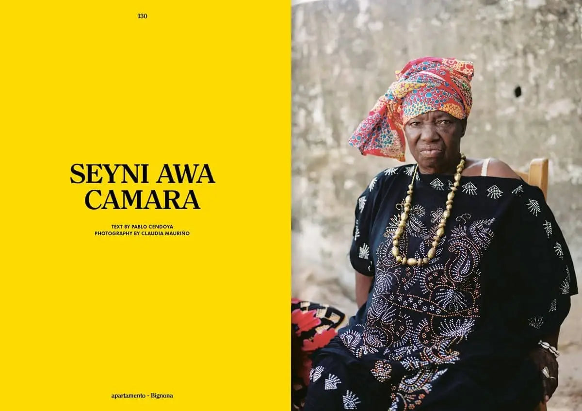 A woman in colorful traditional clothing sits outdoors, beaded necklaces on her neck. The left side is bright yellow with SEYNI AWA CAMARA text, inspired by Spring Summer 2023. Featured in Apartamento Magazine Issue #31 by Apartamento.