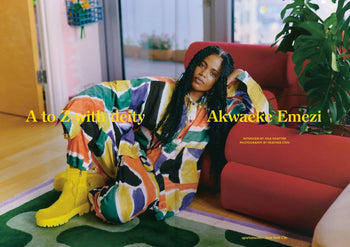 A person in a vibrant outfit and yellow boots sits by a red sofa in a modern room. Yellow text reads: A to Z with deity Akwaeke Emezi. Featured in Apartamento Magazine Issue #32 by Apartamento.