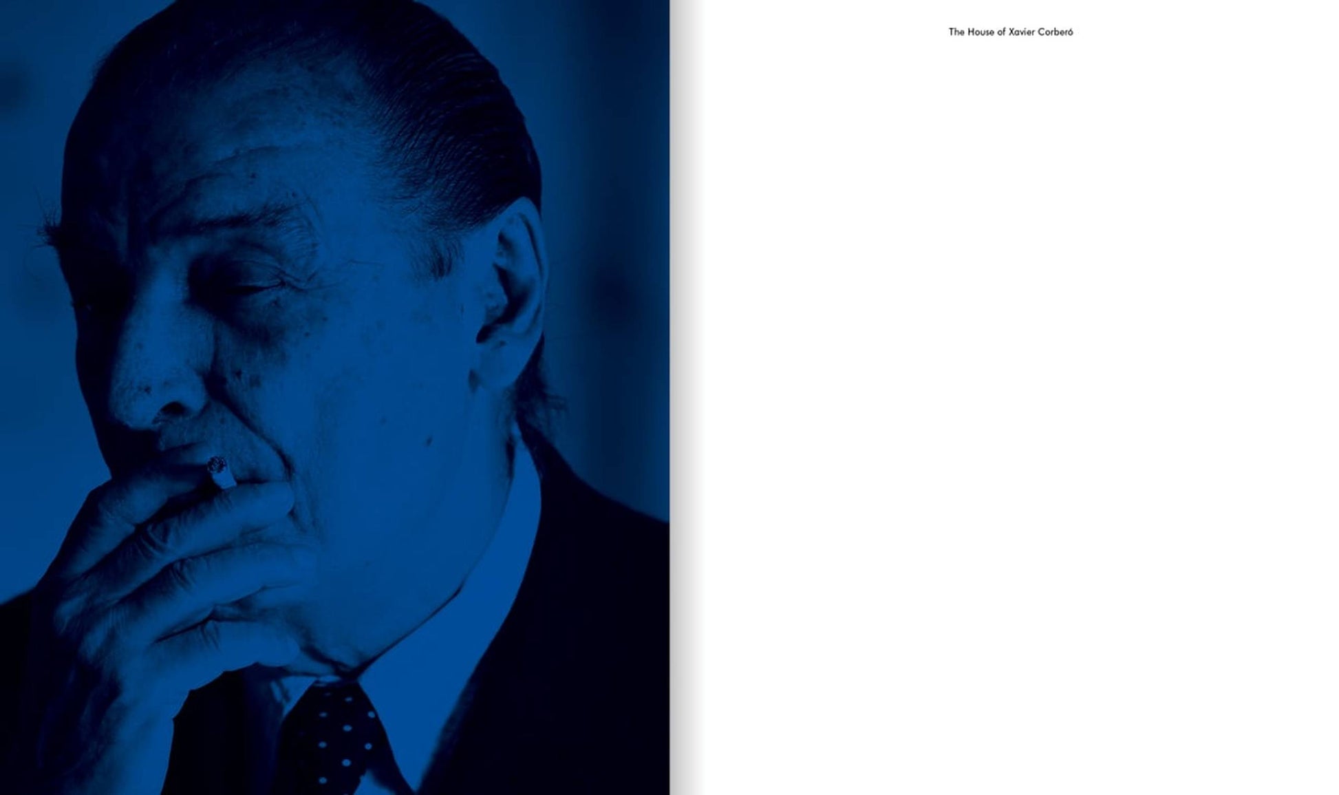 A man in a suit, his face shadowed and tinted blue, holds a cigarette to his mouth—evoking the enigmatic style of Xavier Corberó—on the cover of Apartamento The House of Xavier Corberó by Apartamento; the right page is blank with small black text at the top.