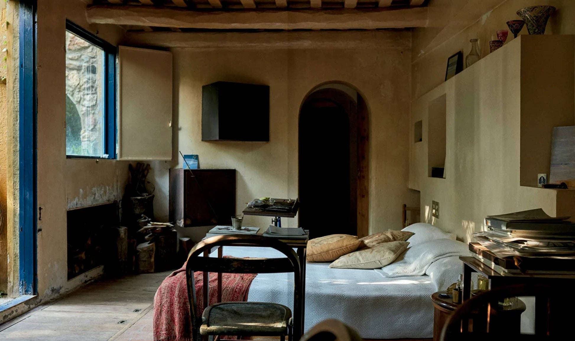 Apartamento The House of Xavier Corberó by Apartamento captures a cozy, rustic bedroom in Esplugues de Llobregat with wooden beams, unmade bed, bookshelves, and natural light—evoking Corberó’s surrealist artistic spirit.