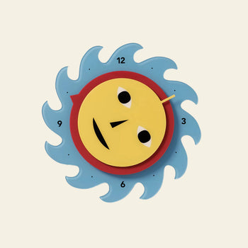 The Areaware Everybody Clock by Areaware features a whimsical sun-shaped design, yellow face with blue wavy rays, and numbers 3, 6, 9, and 12 marking the hours on a light background.