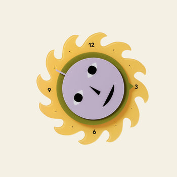 The Areaware Everybody Clock by Areaware features a playful sun-shaped design with a yellow sunburst, purple face, black eyes, smiling mouth, and bold numbers 3, 6, 9, and 12 marking the hours for a vibrant look.