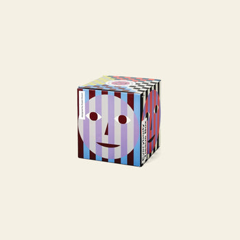 The Areaware Everybody Tissue Box features colorful vertical stripes in blue, purple, and red on a beige cube, accented with abstract smiling faces.