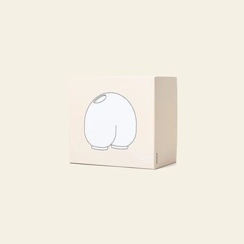 The Areaware Kirby Vase Enny by Areaware features a beige box with a simple black outline of its rounded, cartoonish form facing away, making it perfect for gifting with floral arrangements or pairing with your best bud vase.