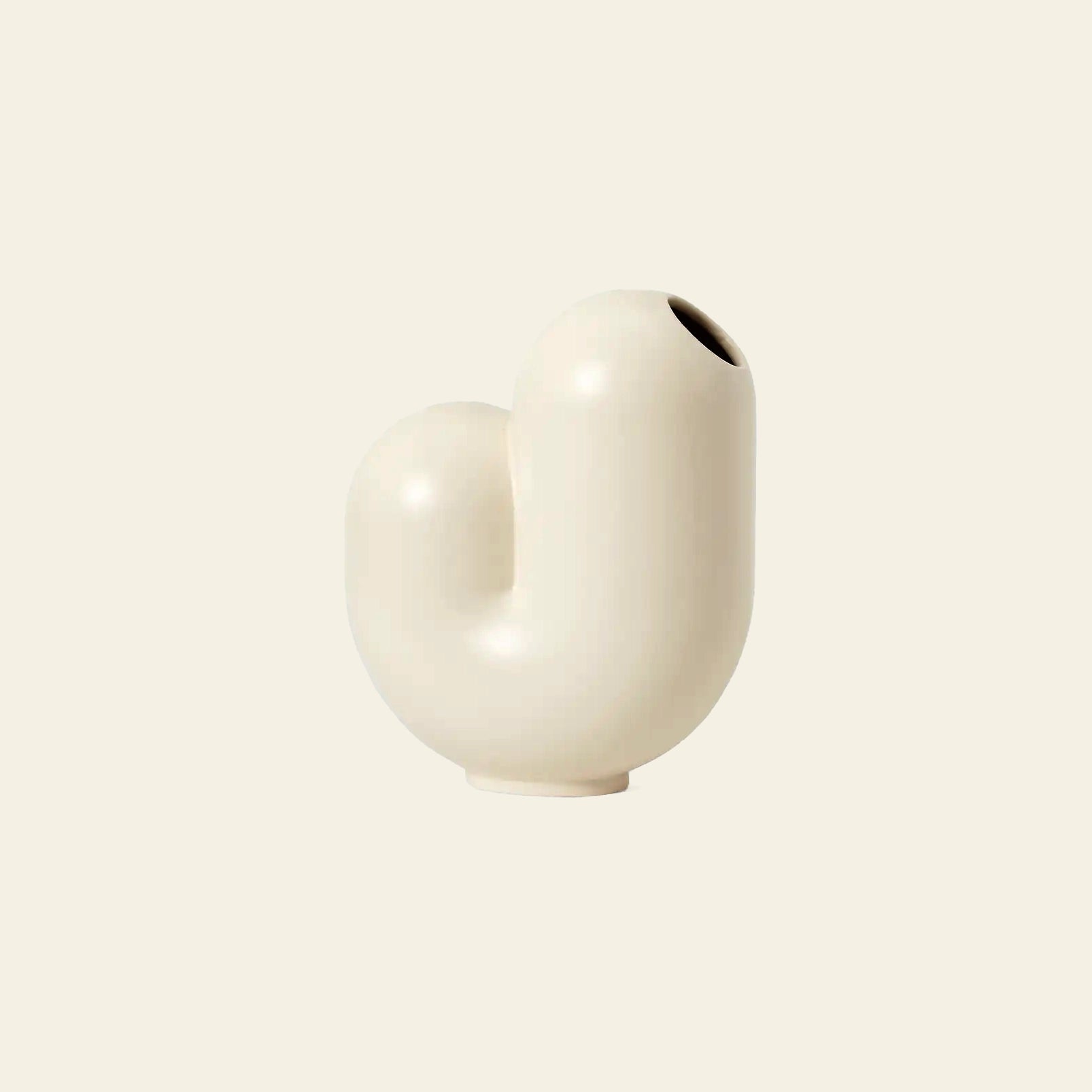 The Areaware Kirby Vase Jay by Areaware is a modern, cream-colored ceramic vase with a smooth, abstract curved shape, perfect as a chic bud vase for stylish floral arrangements. Displayed against a simple beige background.