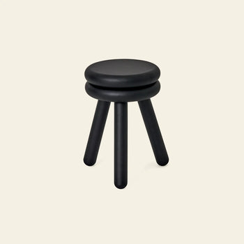 The Areaware Pluma Stool Tall by Areaware is a modern black stool featuring a round, double-layered seat and three cylindrical legs, shown against a plain light beige background.