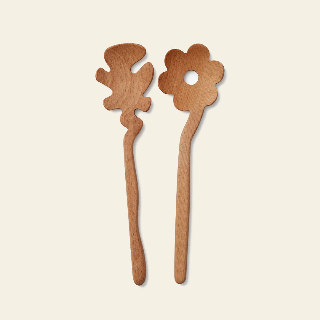 Add playful charm to your table with Areaware Serving Friends - Flowers by Areaware: two whimsical wooden salad servers—one a flower with a central hole, the other an abstract blob—set against a light background.