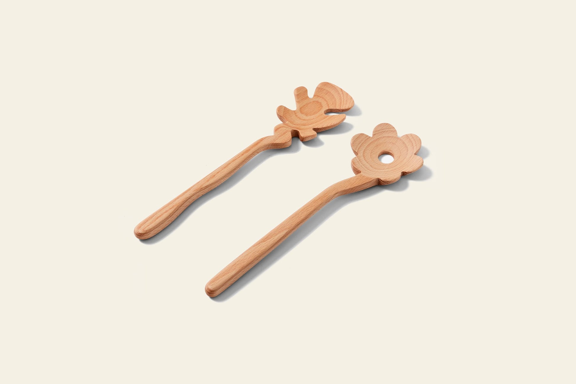 Areaware Serving Friends - Flowers by Areaware: two charming wooden spoons with whimsical flower-shaped flat ends (one solid, one with a hole) are shown side by side on a light background.