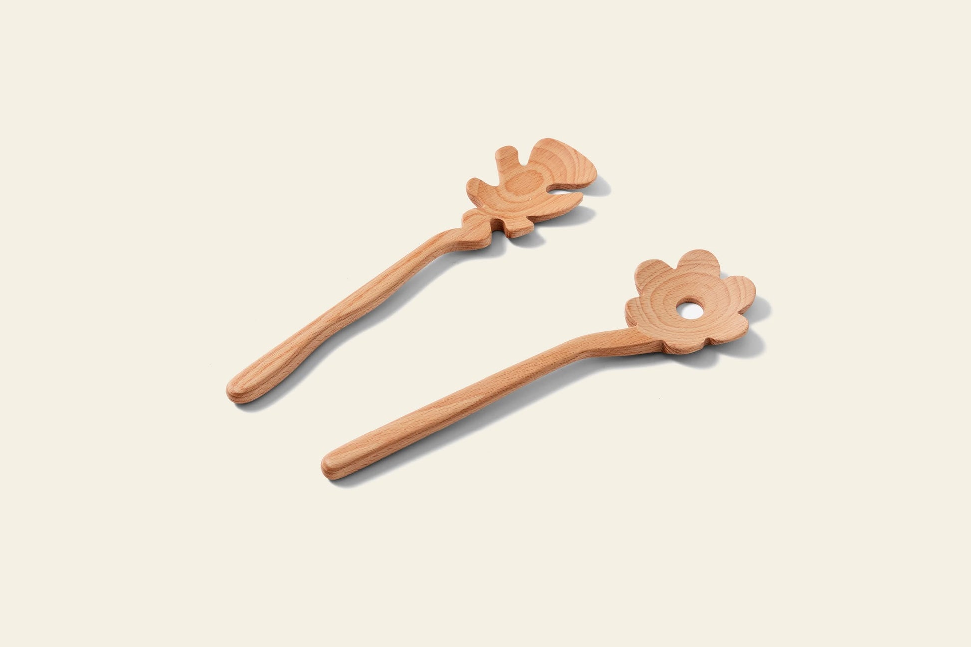 Areaware Serving Friends - Flowers by Areaware features two charming wooden spoons with whimsical flower-shaped ends—one solid, one with a playful hole—each with a long handle, displayed on a light background.