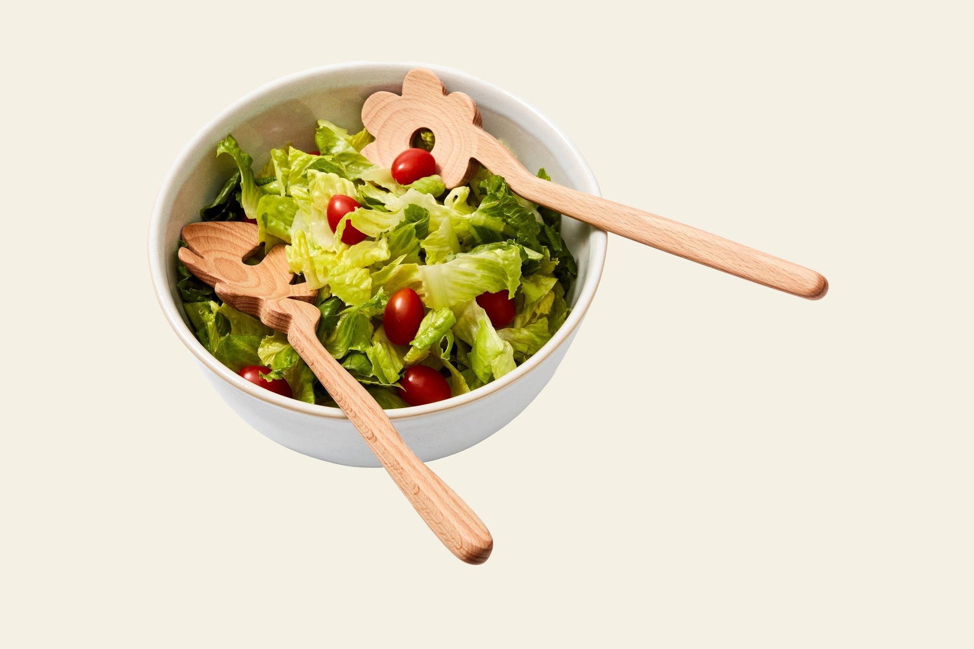 The Areaware Serving Friends - Flowers, a white bowl by Areaware, is filled with leafy green lettuce and cherry tomatoes, topped with charming wooden spoons.