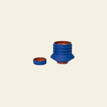 The Areaware Strata Plant Vessel by Areaware, shown open with its lid beside it on a beige background, blends everyday function with sculptural design inspired by Simone Brewster.