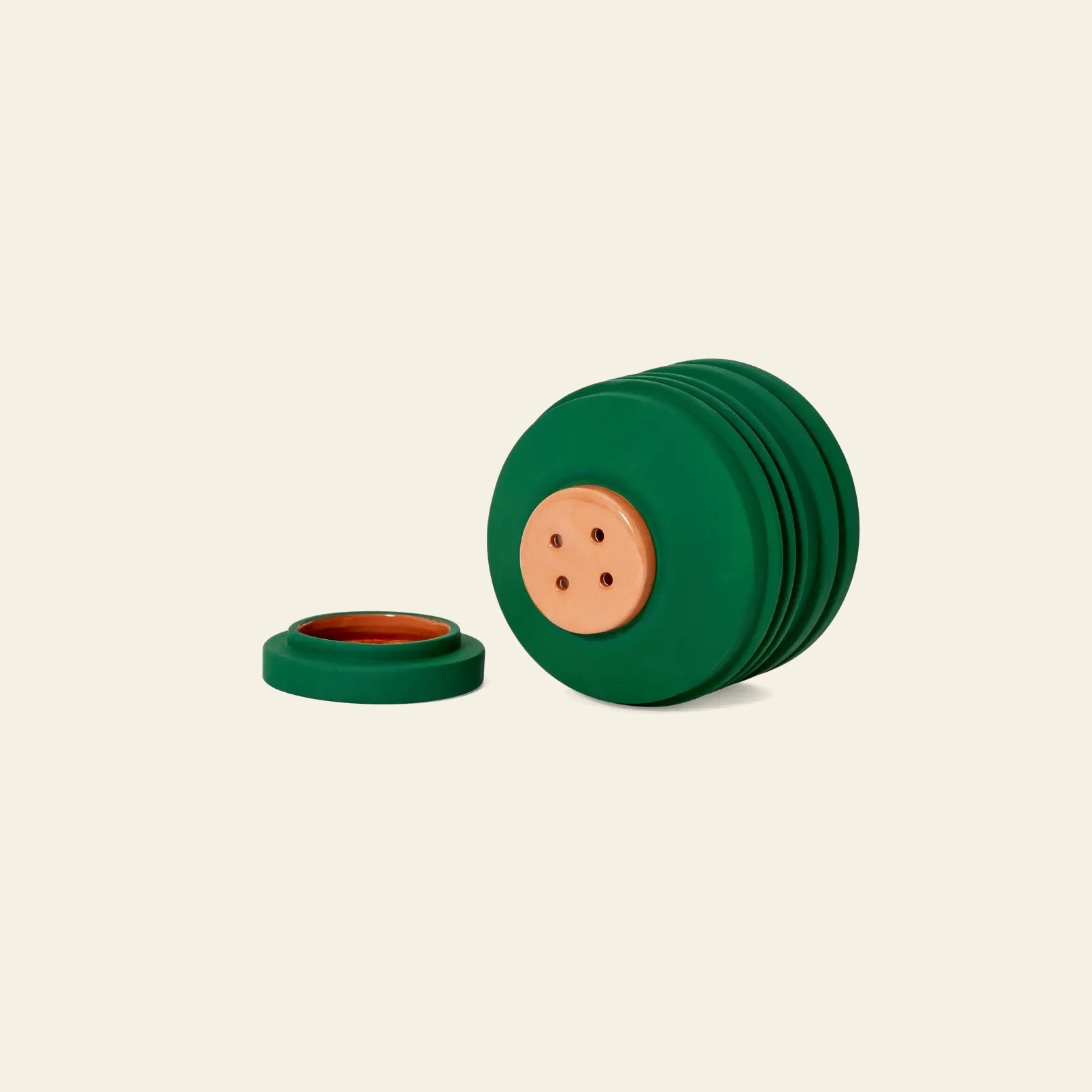 A stack of green, round objects with tan centers and four holes, plus a separate lid-like piece, displays the sculptural Areaware Strata Plant Vessel by Areaware on a plain beige background.
