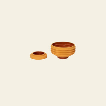 Two orange and brown Areaware Strata Plant Vessels by Areaware are displayed on a beige background. The right vessel has a ridged, sculptural planter-like design, while the left one is small and shallow.