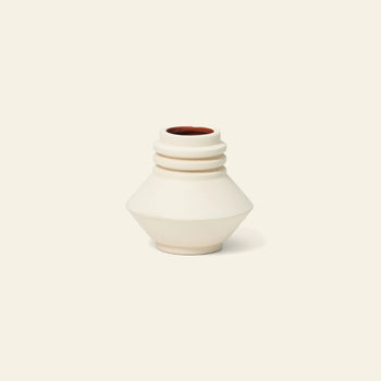 The Areaware Strata Vase Mini by Areaware is a small, cream ceramic vase featuring a geometric, angular shape with three ridges by the narrow opening and a reddish-brown interior—perfect for adding sculptural style to any space. Shown on an off-white background.