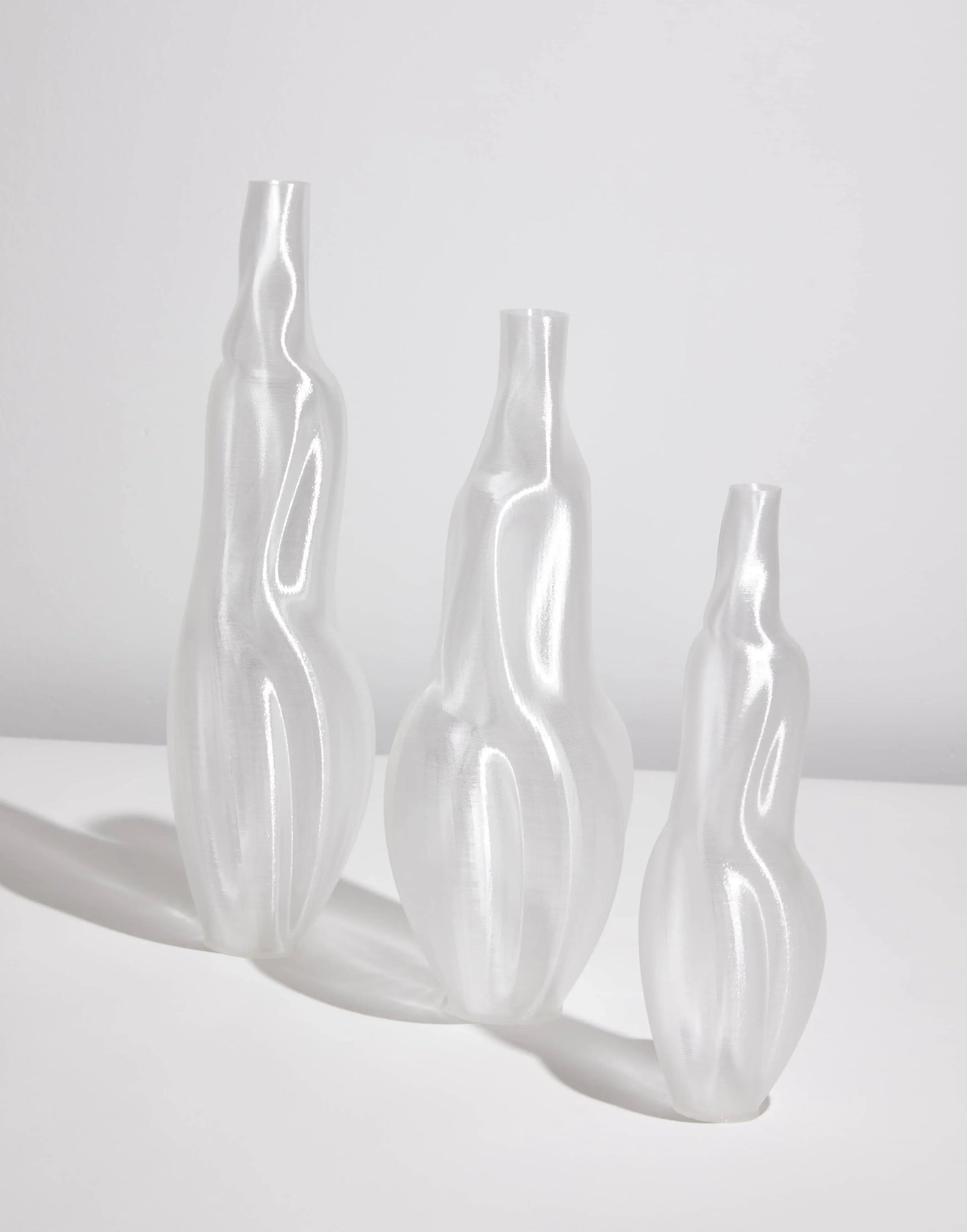 The Argot Studio Éson Vessel, Medium by Argot Studio stands on a white surface against a light gray background, its translucent and sculptural form recalling modern vase design and the elegance of hand-blown French glassware.