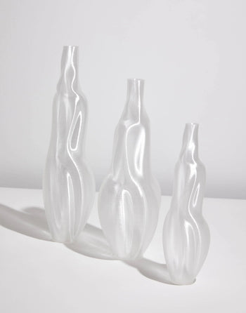 The Argot Studio Éson Vessel, Small by Argot Studio features a translucent, sculptural form with organic curves, standing on a white surface against a light gray background—a modern nod to hand-blown French glassware.