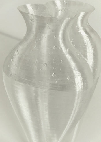 The Argot Studio Soeurs Vase by Argot Studio features a translucent, wavy design with visible air bubbles and a curving, organic shape, standing out against a plain light background.