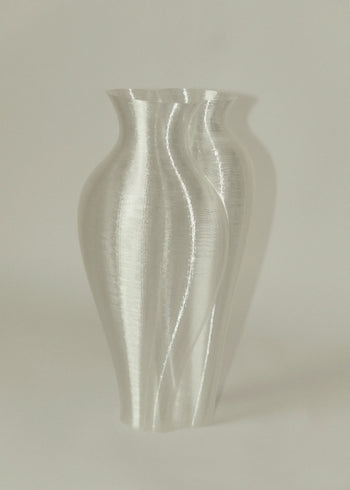 The Argot Studio Soeurs Vase, a modern translucent piece by Argot Studio, features a wavy 3D printed design and texture, shown against a plain light background with a soft shadow highlighting its unique shape.