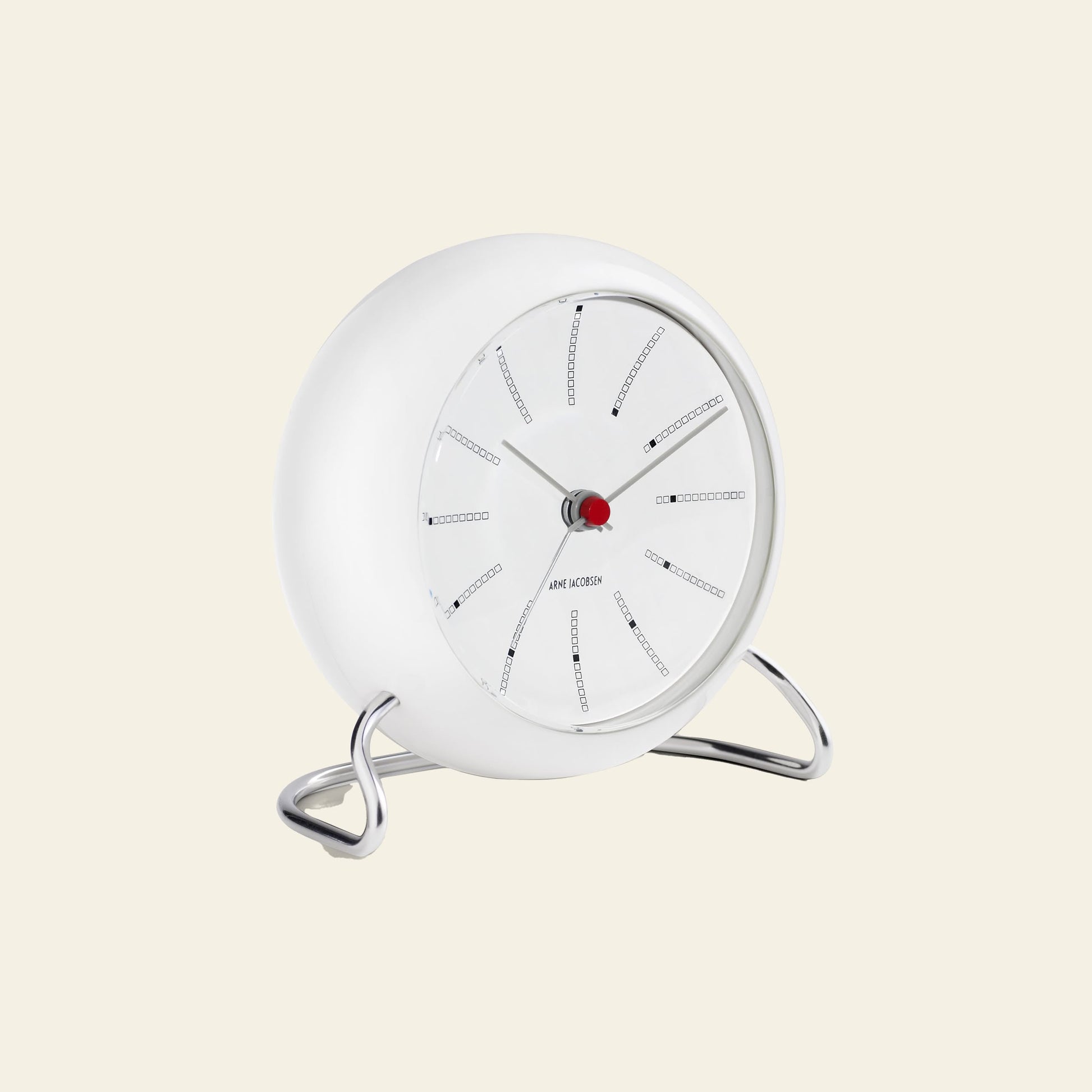 The Arne Jacobsen Bankers Table Clock 11cm is a modern, round white clock with minimalist black hour and minute hands, a red second hand, thin black hour marks, and sits on a curved chrome stand. Brand: Arne Jacobsen.