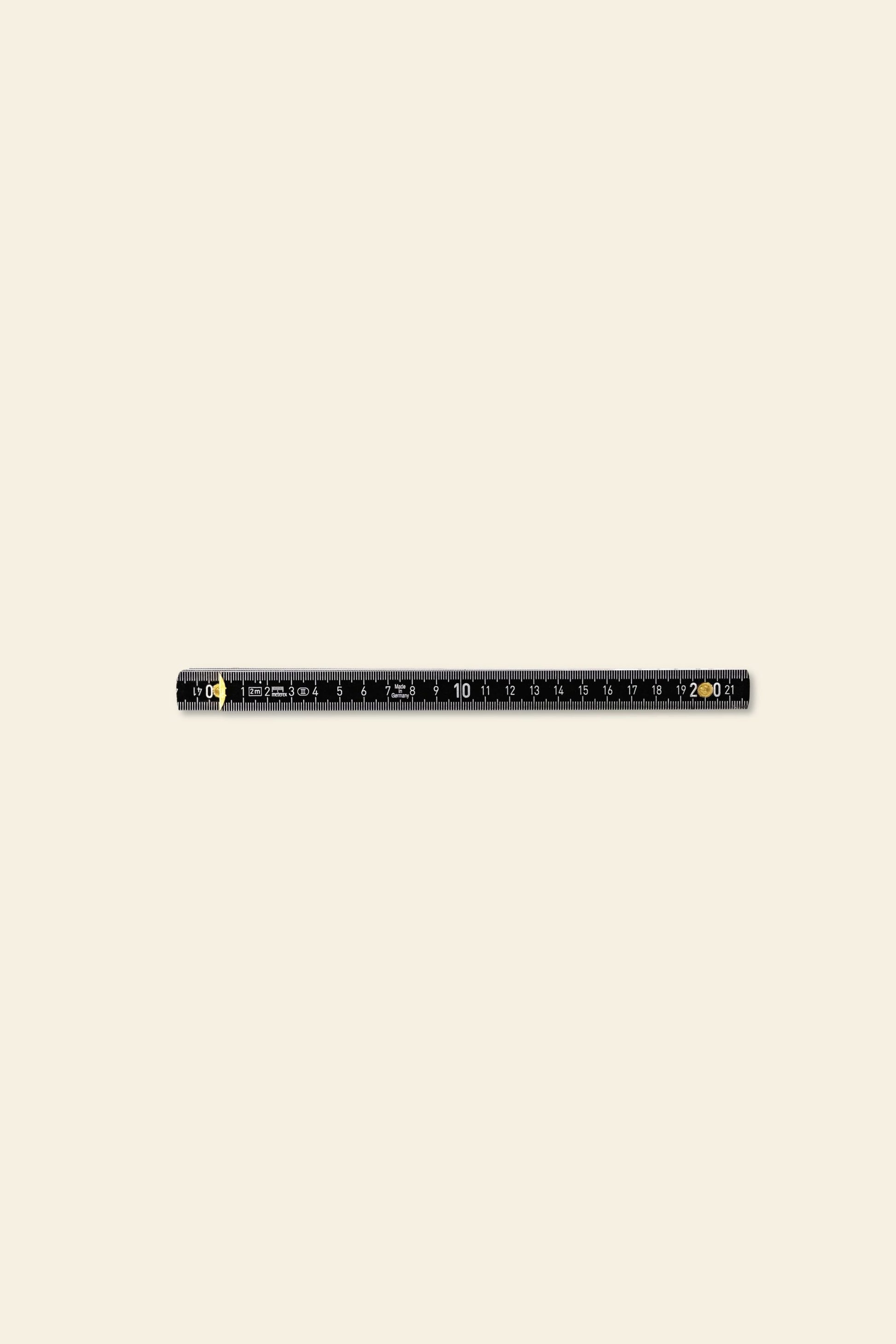 The Artek Folding Ruler by Artek, featuring both inch and centimeter markings for precise measurement, is displayed horizontally on a plain beige background.