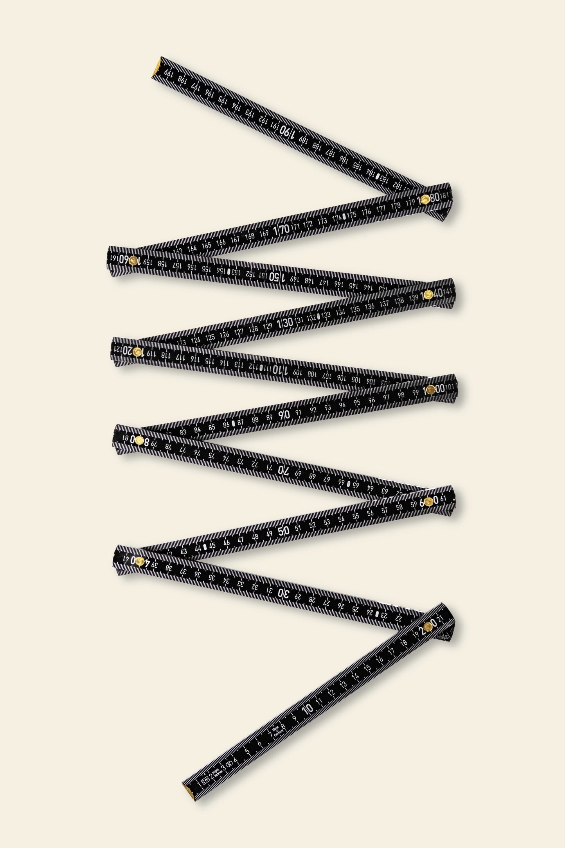 The Artek Folding Ruler by Artek, featuring black finish, white markings, and yellow joint accents, is laid out in a zigzag on a light beige background—perfect for accurate measurements in wood projects.