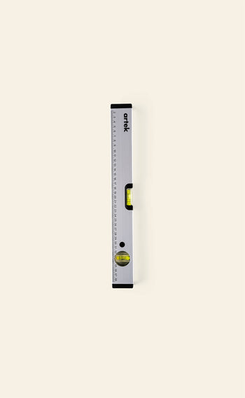 The Artek Level by Artek, a silver aluminum tool with measurement markings and two bubble vials for precision, stands vertically on a light beige background.