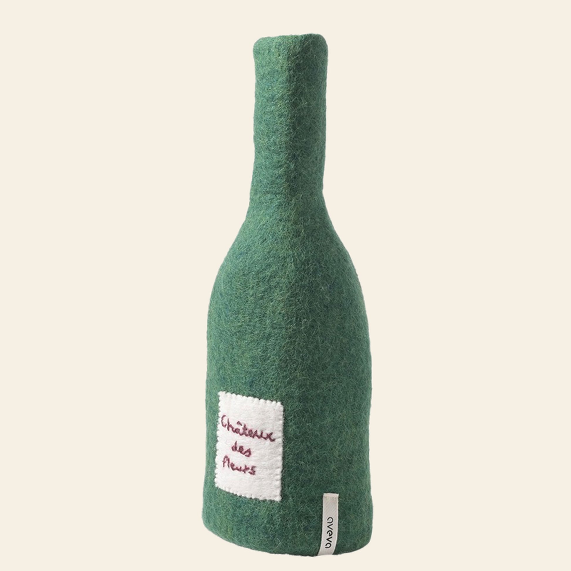 The Aveva Design Bottle/Vase Cover - Chateau Des Fleurs by Aveva Design is a green felt wool cover shaped like a wine bottle, with an embroidered white label and base tag—a charming, whimsical vase accessory.