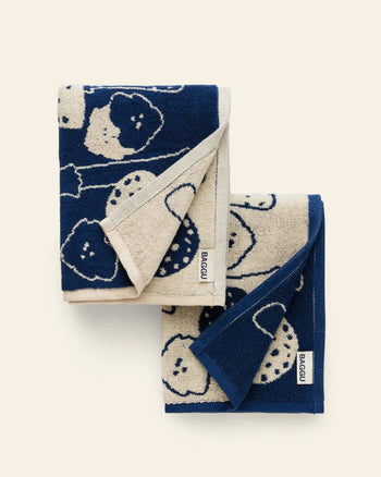 The BAGGU Hand Towel Set of 2 by BAGGU features playful blue and beige towels with a cloud or sheep pattern, stacked neatly against a light backdrop. Each towel has a small white BAGGU label sewn onto its edge.