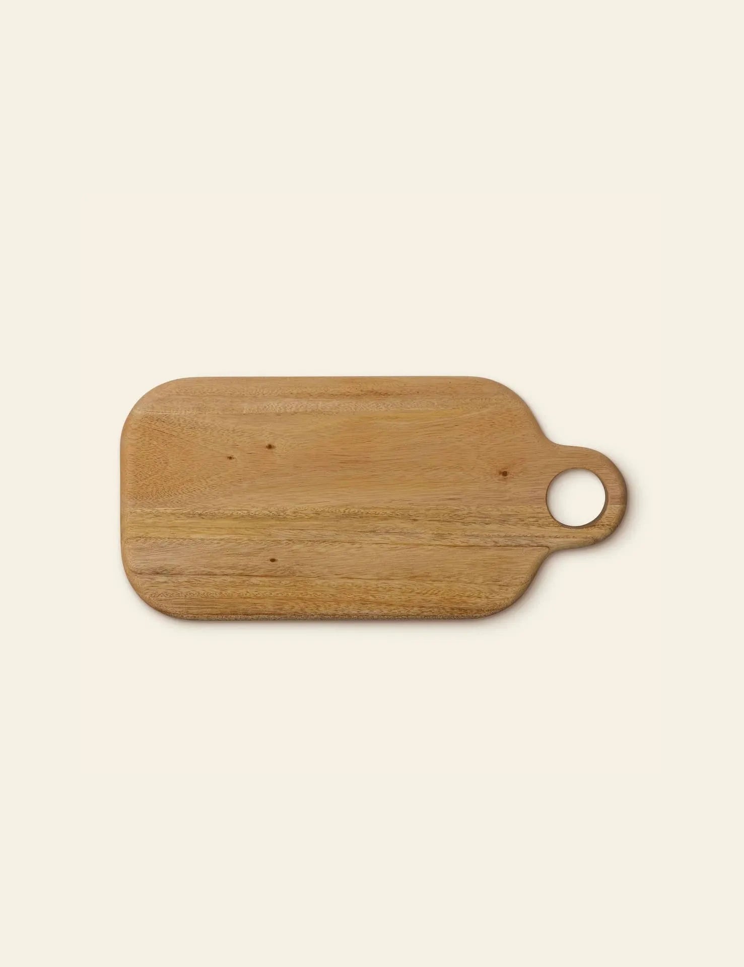 The Bloomingville Abbas Cutting Board by Bloomingville is a rectangular mahogany board with rounded corners and a circular handle on the right, ideal for meal prep and pictured on a light beige background.
