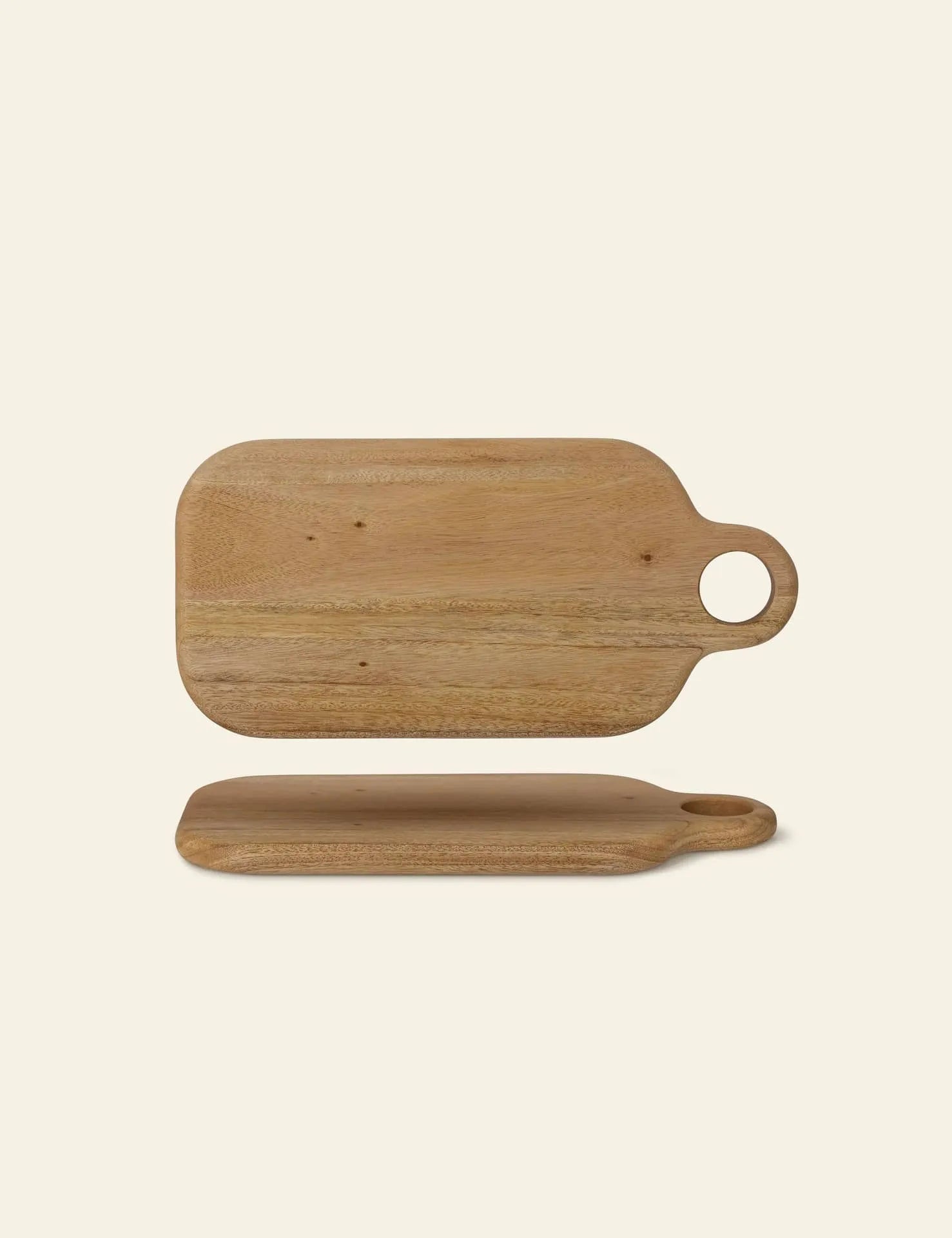 The Bloomingville Abbas Cutting Board by Bloomingville features a rectangular design in mahogany wood with rounded edges and a circular handle, shown from top and side views on a plain light background.